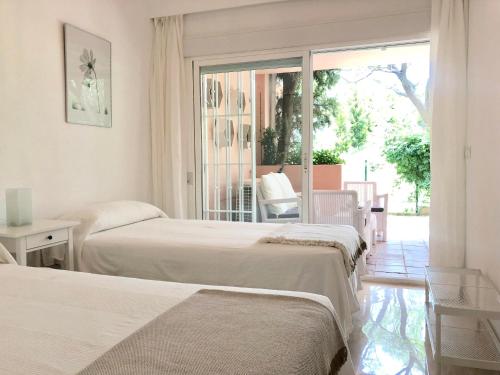 sypialnia z 2 łóżkami i oknem z patio w obiekcie Apartamento Guadalmina - Golf & Playa - Marbella w Marbelli
