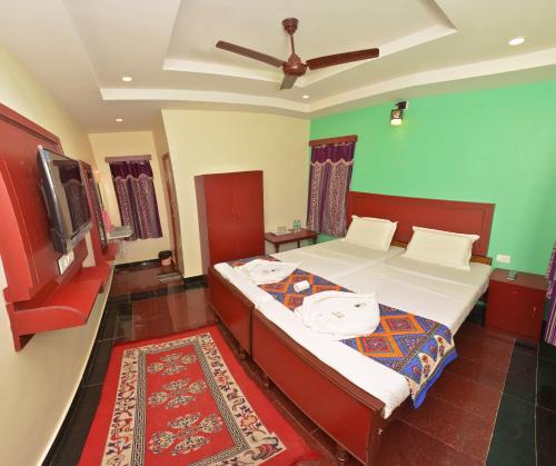 a bedroom with two beds and a tv in it at Siva Guest House in Mahabalipuram