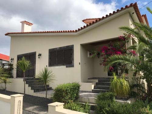 a white house with plants in front of it at Holiday House, São Roque do Pico in Cais do Pico