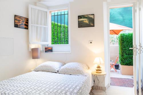 une chambre blanche avec un lit et une fenêtre dans l'établissement Place du Pin, à Nice