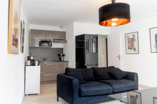 a living room with a blue couch and a kitchen at Place du Pin in Nice