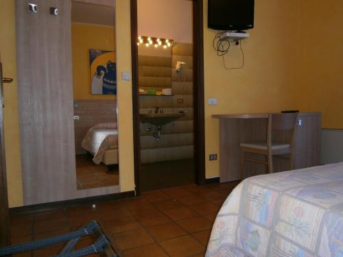 a room with a bedroom with a sink and a mirror at Hotel Chiara in Sirmione