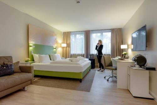 a woman standing in a hotel room with a bed at Congress Hotel Mercure Nürnberg an der Messe in Nürnberg