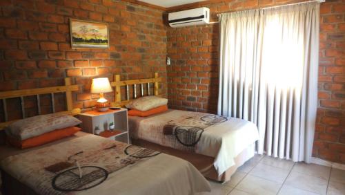 1 dormitorio con 2 camas y pared de ladrillo en Pondoki Rest Camp en Groutfontein