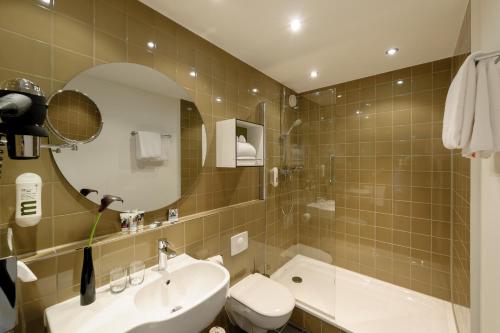 a bathroom with a sink and a toilet and a mirror at Congress Hotel Mercure Nürnberg an der Messe in Nürnberg