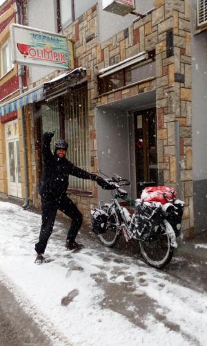 a man standing in the snow next to a motorcycle at Hostel Olimpik in Negotin