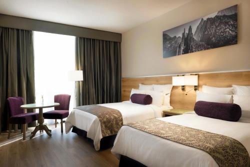 a hotel room with two beds and a table at Krystal Monterrey in Monterrey