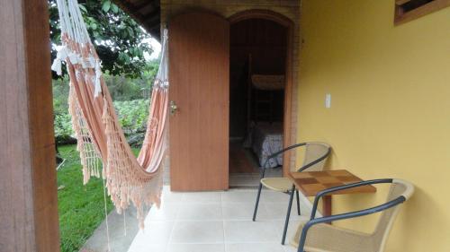 a patio with chairs and a table and hammocks at Pousada Chácara do Rio in Lumiar