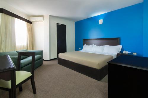 a hotel room with a bed and a blue wall at CHN Hotel Monterrey Santa Fe in Monterrey