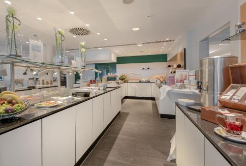 a large kitchen with a buffet line with food at Congress Hotel Mercure Nürnberg an der Messe in Nürnberg