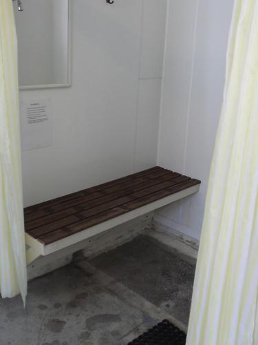 a wooden bench sitting in a corner of a room at Whitianga Campground in Whitianga