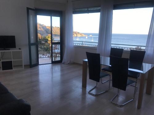 una sala da pranzo con tavolo, sedie e vista sull'oceano di Baia Taormina Apartment a Giardini Naxos