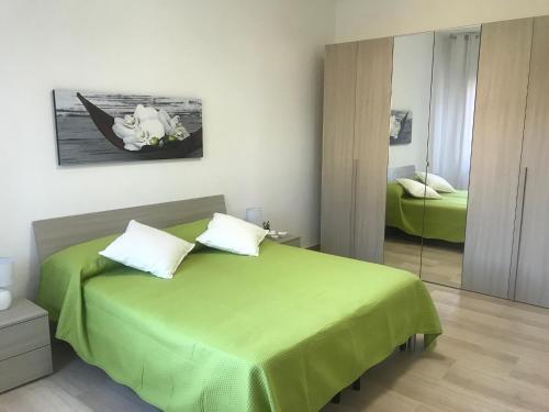 1 dormitorio con cama verde y espejo en Baia Taormina Apartment, en Giardini Naxos