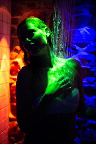 a woman is covered in green and purple lights at L' Aia Resort in Trentinara