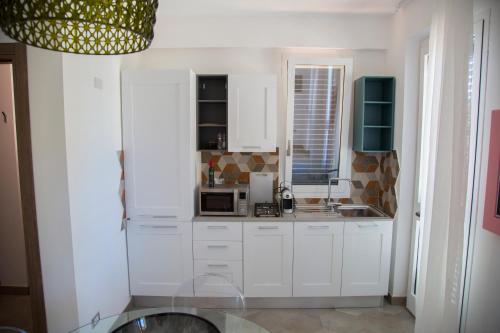 a kitchen with white cabinets and a microwave at Le Suites del Carrubo in Favignana