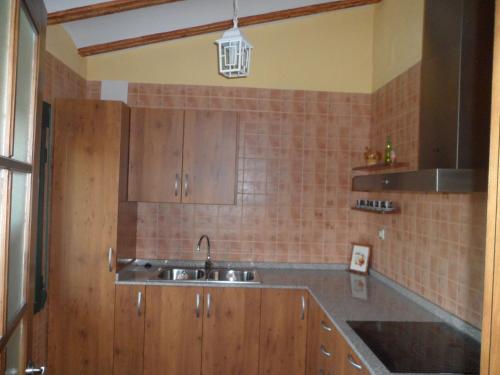 a kitchen with wooden cabinets and a sink at Casa la Peña in Alpera