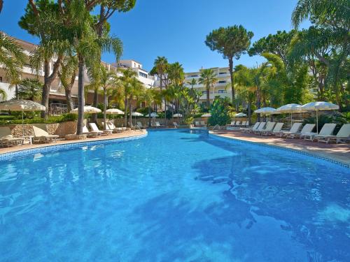 a large swimming pool with chairs and umbrellas at Vale Do Garrao Villas in Vale do Lobo