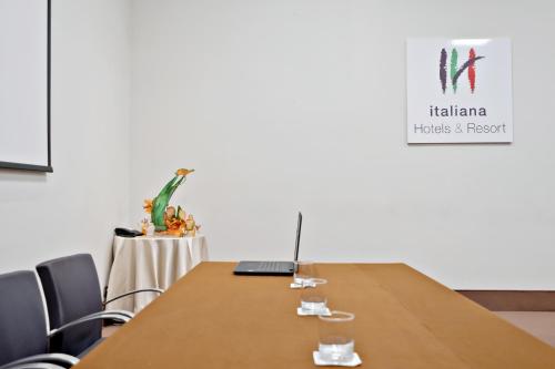 a conference room with a table with a laptop and chairs at Italiana Hotels Cosenza in Cosenza