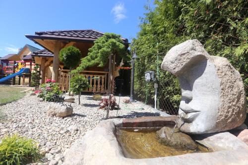 a statue in front of a house with a fountain at Sosnowe Domki in Rewal