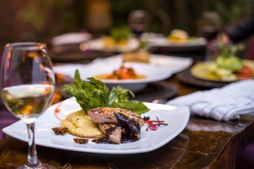 a table with plates of food and a glass of wine at Pisac Inn in Pisac