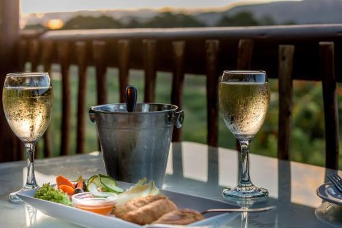 マレラネにあるRio Vista Lodgeのワイン2杯、テーブルの上に盛り付けられた料理