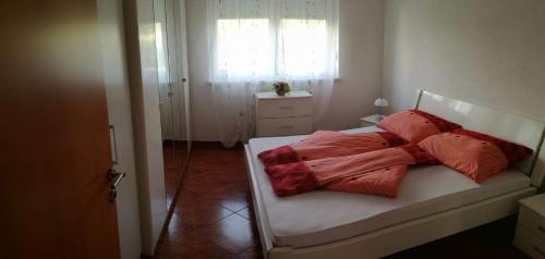 Apartments Barbic في أوماغ: غرفة نوم عليها سرير ومخدات حمراء