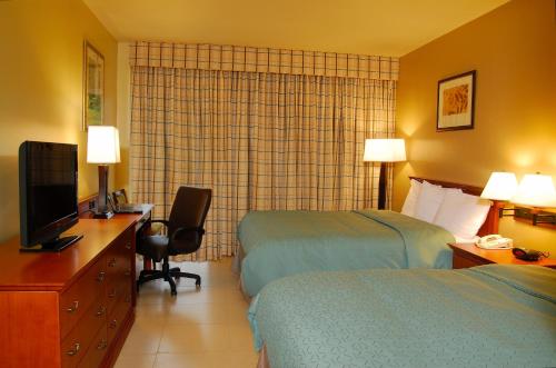 a hotel room with two beds and a desk and a television at Radisson Hotel Panama Canal in Panama City