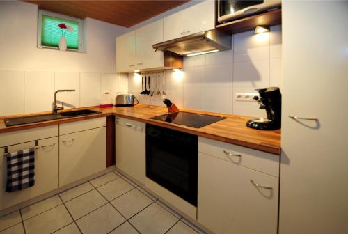 eine Küche mit weißen Schränken und einem Waschbecken in der Unterkunft Im Kirchberg in Lieser