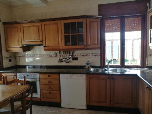 a kitchen with wooden cabinets and a sink at Chalet vacacional en segunda linea de playa in Foz