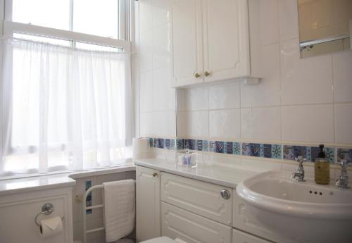 a white bathroom with a sink and a window at Carlton Court in Torquay