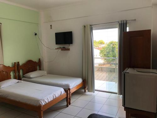 a room with two beds and a tv and a window at Epílogo Palace Hotel in Rio Branco