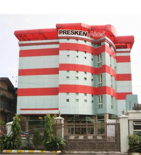 un edificio rojo y blanco con un cartel en él en Presken Hotel at International Airport Road en Ikeja