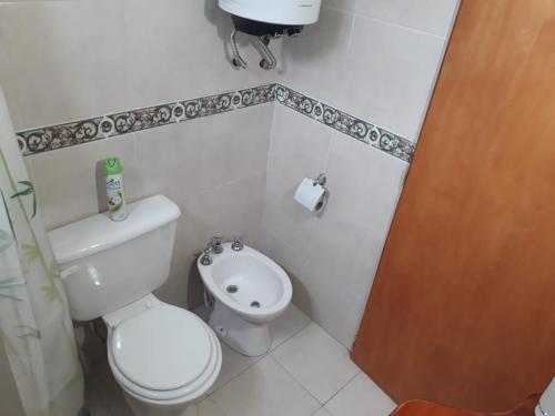 a white bathroom with a toilet and a sink at Las Hortensias in Junín