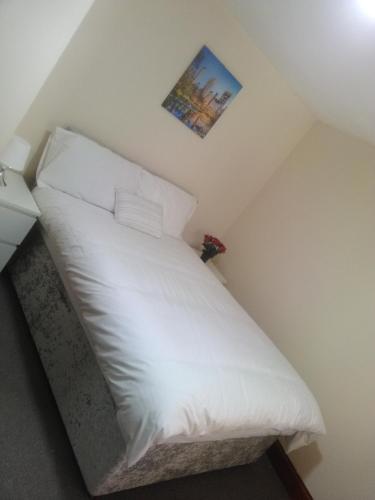 a bed with white sheets and pillows in a room at West Brae Inn in Paisley