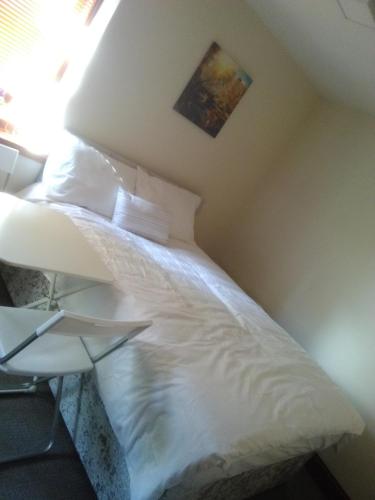 a bedroom with a bed with white sheets and a window at West Brae Inn in Paisley