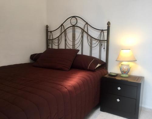 a bedroom with a bed with a red bedspread and a lamp at Residence Las Trojes Cdmx in Mexico City