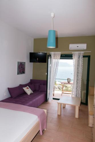 a bedroom with a purple couch and a view of the ocean at Elina Apartments in Parga