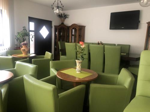 una habitación con sillas verdes y una mesa con un jarrón de flores en Pensiunea La Răducu en Vişeu de Sus
