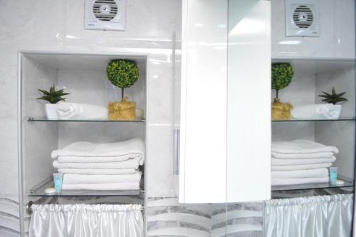 a bathroom with white towels and plants on shelves at Orbi Residence Duplex Apartment in Batumi