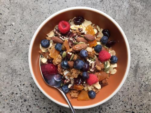 a bowl of granola and berries with a spoon at 1 Hotel Central Park in New York