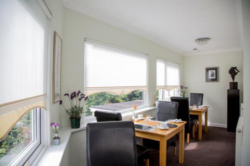 a dining room with a table and chairs and windows at Carlton Court in Torquay