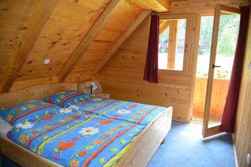 ein Schlafzimmer mit einem Bett in einem Blockhaus in der Unterkunft POČITNIŠKA HIŠA JURČEK POKLJUKA in Goreljek