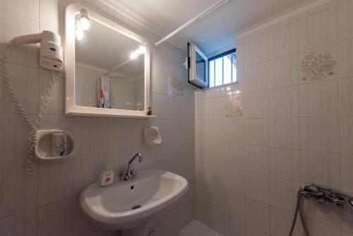 Baño blanco con lavabo y espejo en Villa Tasos Koutsoubos, en Koroni