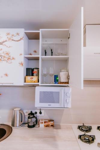 a kitchen with white cabinets and a microwave at Like a home Linda Apartment in Narva