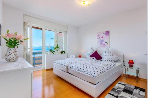 a white bedroom with a bed and a vase of flowers at Jasmina apartment in Rijeka