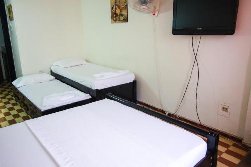 two beds in a room with a tv on the wall at El Velero Apartamentos By DANP in Santa Marta