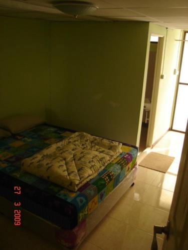 Cama pequeña en habitación con pared verde en Kaset Guesthouse, en Bangkok