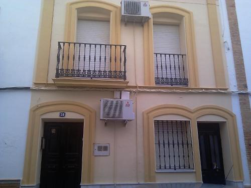 Edificio con 2 ventanas, puerta y balcón en Pensión Ignacio, en Aljaraque
