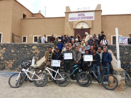 a group of people posing for a picture with their bikes at Kasbah Citoyenne in Agoudal