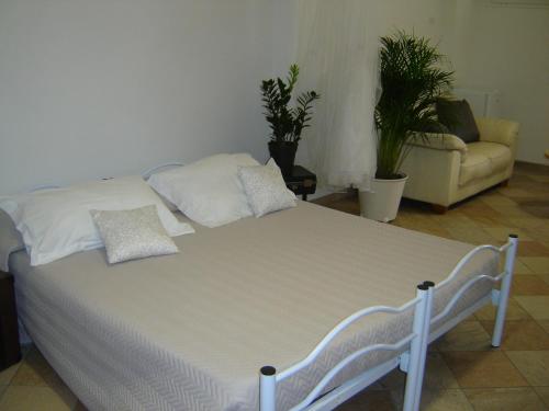 a white bed in a room with plants and a couch at La Dolce Vita B&B in Noli